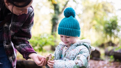 Adult and child in warm clothes exploring the woodland